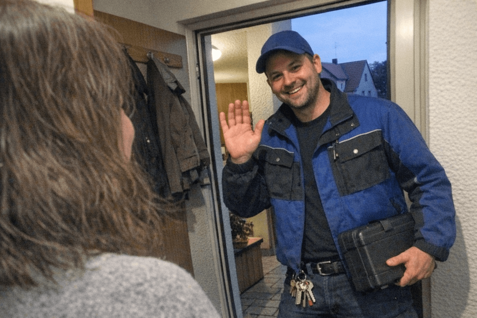 Servicetechniker reicht einer Kundin den neuen Schlüsselbund vor der Haustür