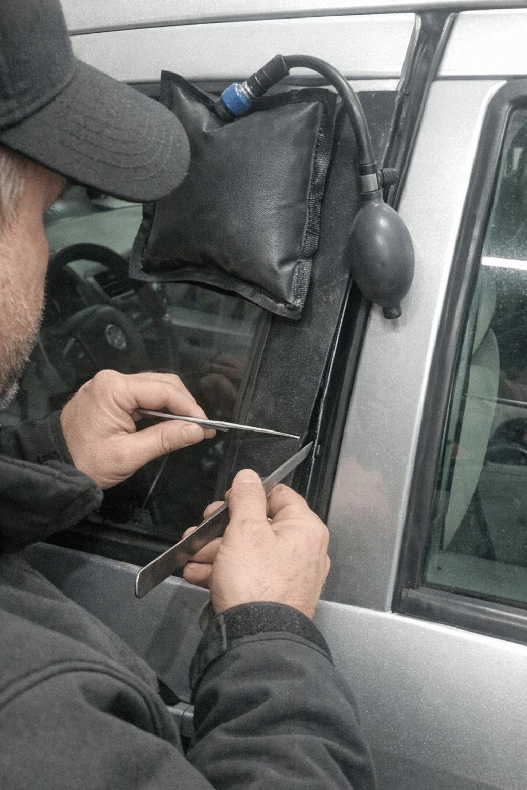 Techniker arbeitet an einem Pkw-Fensterspalt mit speziellem Öffnungswerkzeug und Schutzkeilen